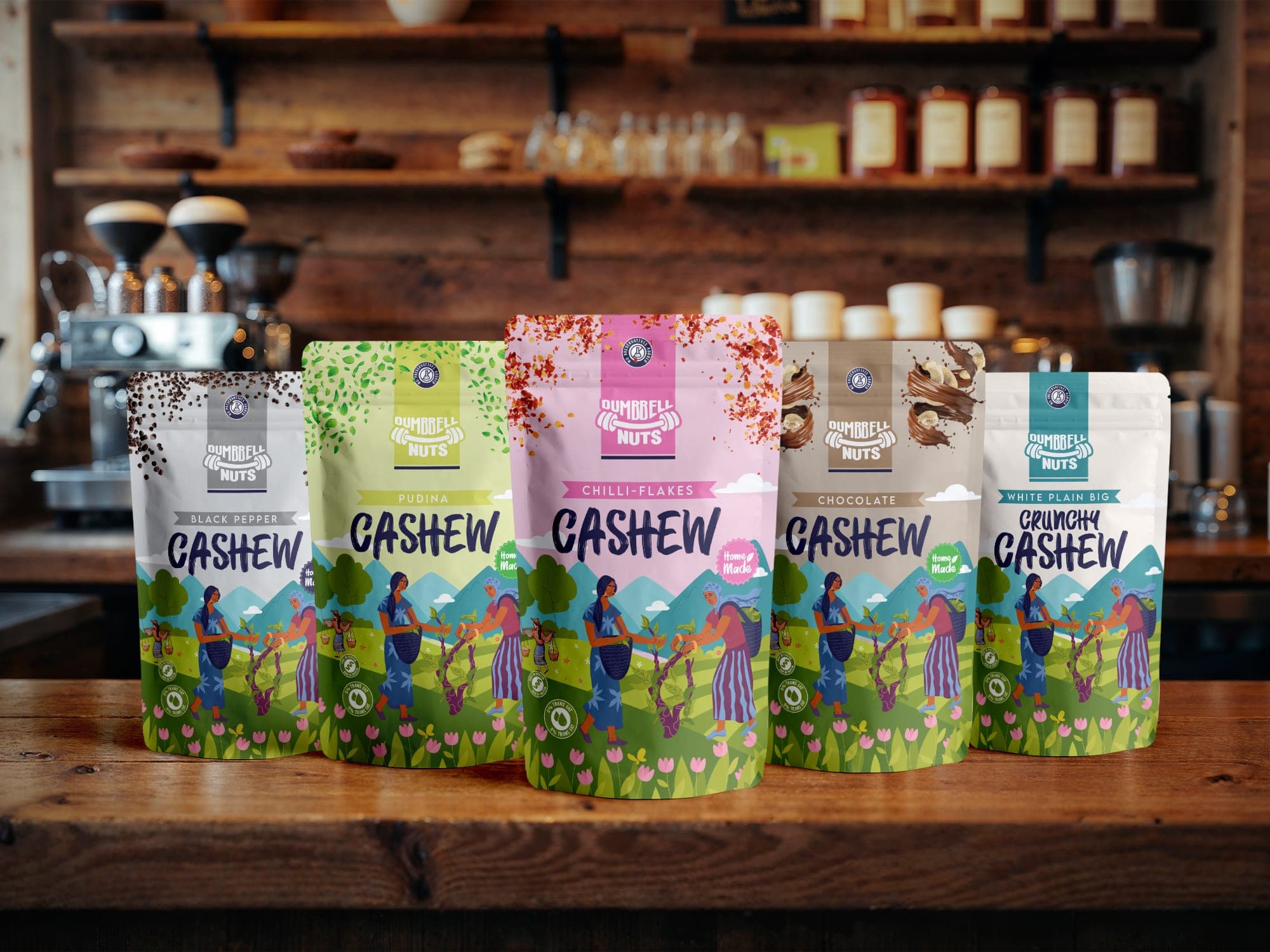 Five Dumbbell Nuts cashew pouches in a row on a wooden café counter, each in a different flavor colorway