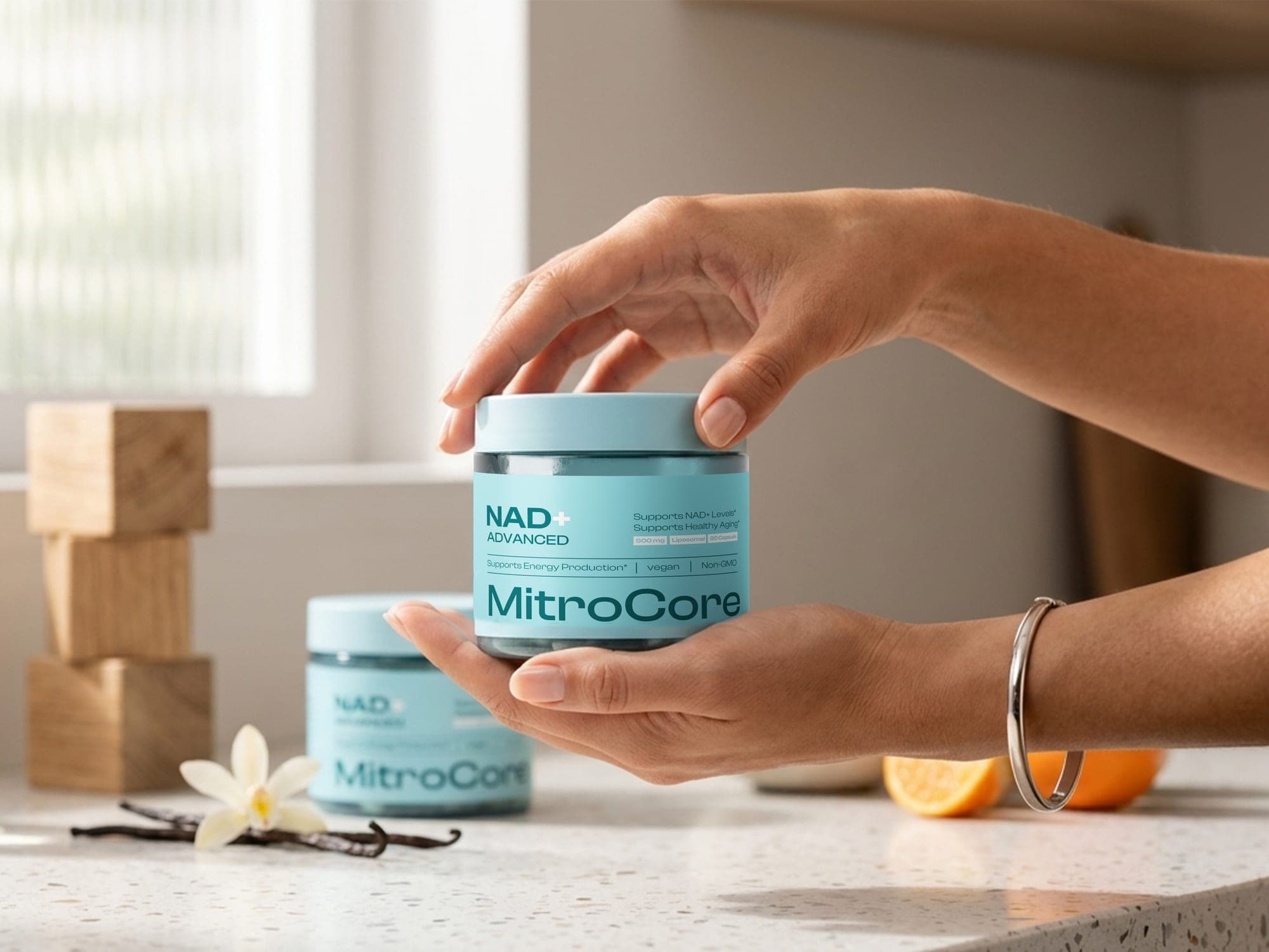 A hand lifting the lid off a MitroCore jar on a countertop styled with vanilla pods and citrus